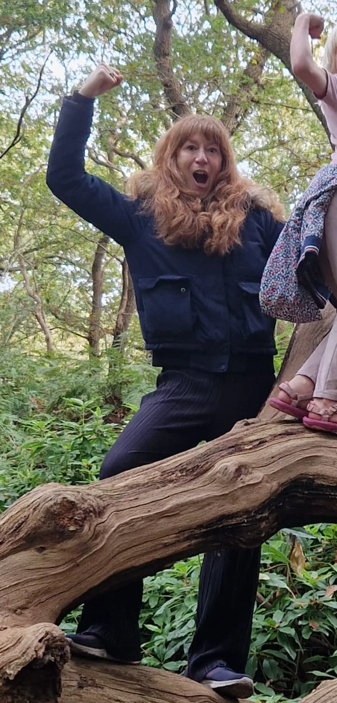 Joyce staat juichend op een omgevallen boomstam in het bos