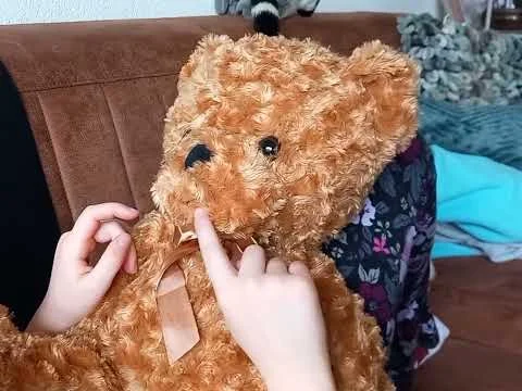 Kinderhanden tikken op de kin van een bruine knuffelbeer