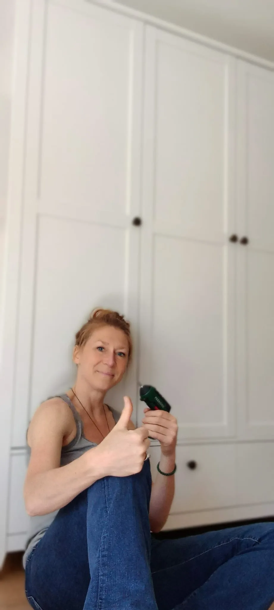 Joyce zit met een accuschroevendraaier voor een zelf in elkaar gezette kast en steekt haar duim op