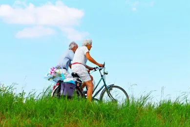 Ouder stel fietst samen over een dijk