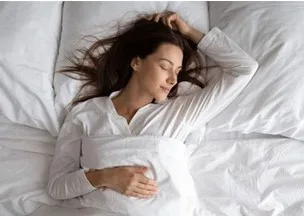 Vrouw slaapt ontspannen in een wit bed