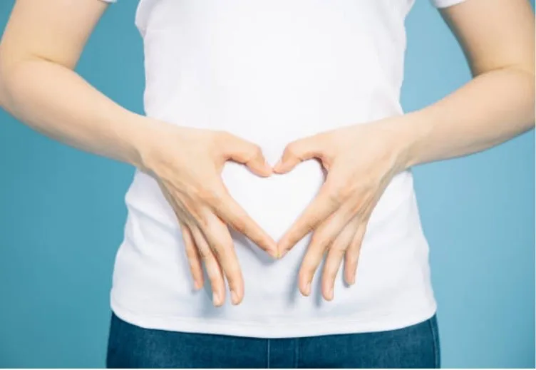 Vrouw vormt een hartje met haar handen op haar buik